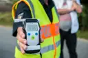 Policjant pokazuje alkomat z wynikiem 0.93 promila. To przekroczenie dopuszczalnej ilości alkoholu w wydychanym powietrzu.