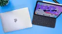 Geschlossenes MacBook neben einem geöffneten iPad Pro mit Tastatur und Apple Pencil.