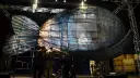 Scena teatralna z wielką, szklaną rybą, w której siedzi człowiek. To może być cud Jonasza.