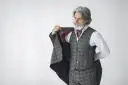Elegancki mężczyzna z siwą brodą i wąsami, ubrany w kraciasty garnitur, prezentuje się jak prawdziwy arbiter elegantiarum.