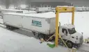 Ciężarówka z naczepą Airgas pod żółtą bramownicą w śnieżny dzień.