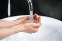 Dłonie łapią strumień wody z kranu. Zastanawiasz się, ile kosztuje kubik wody?