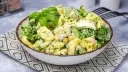 Sałatka z tortellini, brokułów, kukurydzy i jajka w kremowym sosie, udekorowana bazylią.