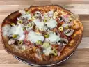 Apetyczna pizza z twarogu z pieczarkami, szynką i oliwkami, z ciągnącym się serem.