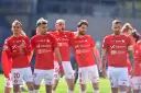 Piłkarze Wisły Kraków w czerwonych strojach, z numerami na koszulkach i spodenkach, świętują. W tle trybuny. #wisla #krakow #transfery