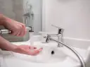 Dłoń pod strumieniem wody z podręcznego bidetu. To proste rozwiązanie do higieny osobistej.
