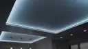 Nowoczesny sufit napinany z subtelnym, niebieskim podświetleniem tworzy relaksującą atmosferę.