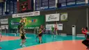 Mecz siatkówki w Zawierciu. Zawodnicy w zielonych strojach walczą o piłkę pod koszem.
