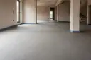 Surowa posadzka betonowa z widoczną linią dylatacji, przygotowana do dalszych prac wykończeniowych.