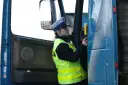 Policjantka w kamizelce odblaskowej i czapce przykłada alkomat do drzwi ciężarówki.