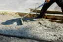 Pracownik rozprowadza świeży beton B25. Czas wiązania betonu zależy od wielu czynników.