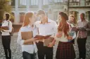 Studenci rozmawiający na kampusie, z książkami i notatkami w rękach. Wszyscy wyglądają na szczęśliwych, jakby właśnie skończyli zajęcia. To idealny obrazek dla osób, które chcą połączyć pracę z nauką, wybierając l4 a studia zaoczne.