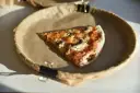 Kawałek pizzy z pieczarkami na brązowym papierze. Zastanawiasz się, ile kalorii ma pizza?