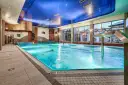 Basen hotelowy z niebieskim sufitem i dużymi oknami, woda w basenie jest turkusowa.