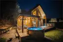 Drewniany domek z jacuzzi i tarasem, idealne miejsce na babia góra noclegi. Oświetlony girlandami, zaprasza do relaksu.