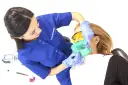 Dentystka zakłada koferdam pacjentce, przygotowując ją do zabiegu.