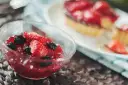 Domowa galaretka z soku z owocami kontra galaretka z proszku. W miseczce galaretka z kawałkami truskawek i borówek.