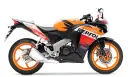 Pomarańczowo-czarny motocykl Honda CBR 125R w barwach Repsol, gotowy do wyścigów.