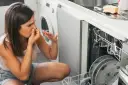Nieprzyjemny zapach ze zmywarki Electrolux? Czas na czyszczenie! Kobieta zatyka nos, widząc brudne naczynia.