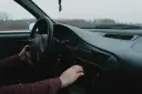 Dłoń kierowcy reguluje radio samochodowe.