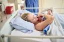 Szczęśliwa mama tuli noworodka. To początek jej urlop macierzyński, pełen miłości i czułości.