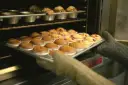 Rękawice wyjmują z piekarnika blachę z gotowymi muffinkami, które idealnie nadają się do przepisu na wilgotne i puszyste muffinki.