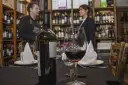 Winiarnia, butelka i kieliszek czerwonego wina na stole. Zastanawiasz się, czy można przewozić alkohol w bagażu rejestrowanym?