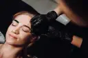 Stylistka w czarnej rękawiczce precyzyjnie maluje brwi klientce. Zastanawiasz się, co ile henna brwi daje najlepsze efekty?