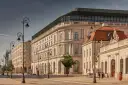 Elegancka kamienica z nowoczesnym dachem, być może najdroższy hotel w Polsce, przy słonecznej ulicy z zabytkowymi latarniami.