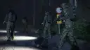 Żołnierze w kamuflażu i robot zwiadowczy na nocnej drodze leśnej.
