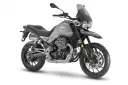 Srebrny motocykl Moto Guzzi V85 TT z charakterystycznym silnikiem V-twin, gotowy na przygodę.