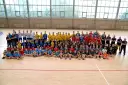 Drużyna Olimp Grodków na hali sportowej. Duża grupa dzieci i młodzieży w strojach sportowych pozuje do wspólnego zdjęcia.