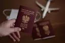 Dłoń trzyma polski paszport. Obok leżą kolejne paszporty, maseczka i samolot. Zastanawiasz się, ile się czeka na paszport?