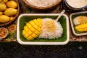 Pyszny mango sticky rice przepis: ryż z mleczkiem kokosowym, świeże mango i chrupiące prażone ziarna. Idealny deser.