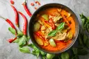 Miseczka czerwonego curry z mięsem, warzywami, papryczkami chili i bazylią.