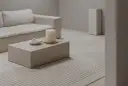 Salon w odcieniach ivory: sofa, stolik kawowy, świeca i dywan z geometrycznym wzorem tworzą spokojną aranżację.