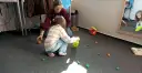 Dzieci bawią się na dywanie, zbierając małe, kolorowe figurki. Www.
