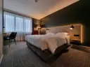 Przytulny pokój w Park Inn Papenburg: wygodne łóżko, designerskie lampy i okna z zasłonami.