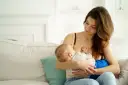 Ciepła chwila karmienia piersią. Mama z miłością patrzy na swoje dziecko, wspierając naturalną laktację.