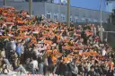 Tłum kibiców na stadionie z szalikami w barwach pomarańczowo-czarnych. Widać napisy "Chrobry" i "Chrobry Głogów".
