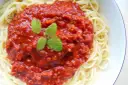 Spaghetti z bogatym sosem bolońskim i listkami mięty.