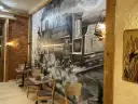 Wnętrze restauracji z muralem przedstawiającym lokomotywę i stoliki.