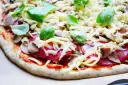 Gotowy do pieczenia przepis na ciasto do pizzy: sos pomidorowy, salami, pieczarki, ser i świeża bazylia.