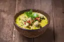 Zielone curry z kurczakiem i chili w drewnianej misce na desce.