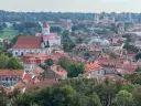 Widok na Wilno z wzgórza Giedymina. Czerwone dachy, białe kościoły i zielone drzewa tworzą malowniczy krajobraz.