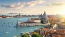Venice cityscape with canals, boats, and historic buildings under a sunny sky.