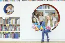 Dzieci z radością pozują z literami "AMAKids" w bibliotece.