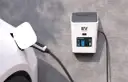 Biały samochód elektryczny podłączony do ładowarki EV na ścianie.
