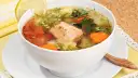 Aromatyczna zupa rybna przepis babci z łososiem, pomidorami, marchewką i ziemniakami, ozdobiona cytryną i natką.
