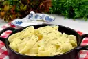 Pappardelle w kremowym sosie alfredo, posypane świeżo mielonym pieprzem, podane w czarnym naczyniu na czerwono-białej kratce.